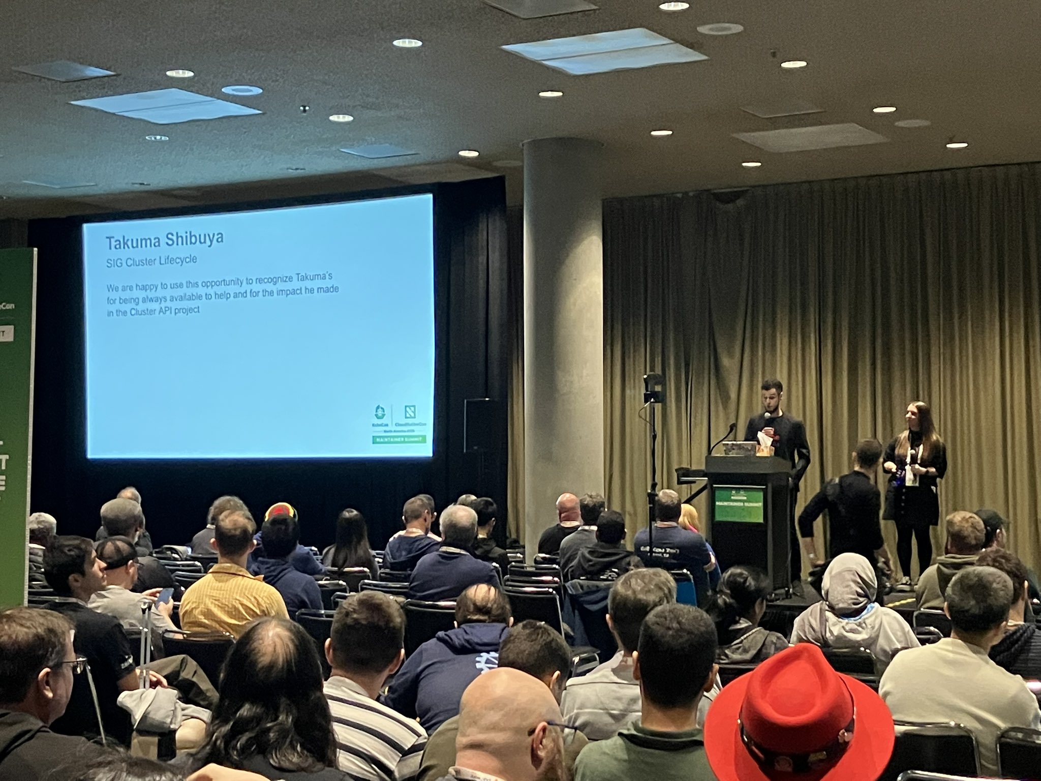 Maintainer Summit での Kubernetes Contributor Award 2025 授賞の様子。スクリーンに「Takuma Shibuya / SIG Cluster Lifecycle」と受賞理由が映し出されている